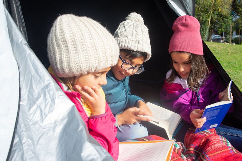 children reading books in a tent