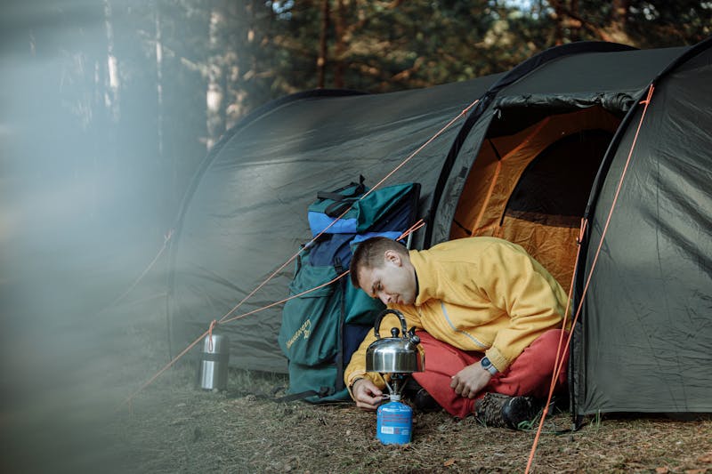 man sitting in a tent lighting a lantern