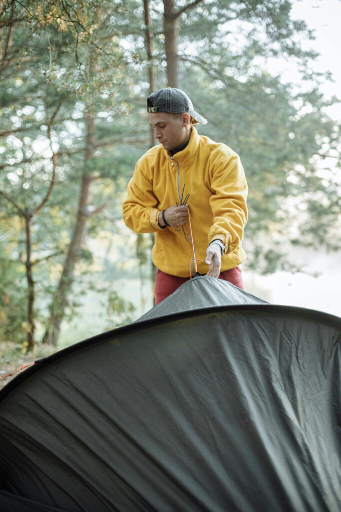 man putting a tent up in the rain